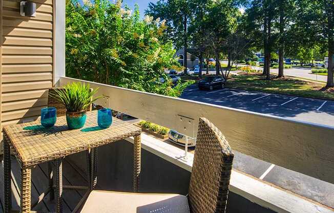 A patio with a table and chairs overlooking a parking lot.