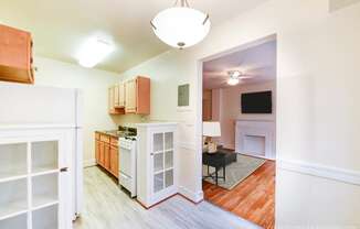 kitchen with gas range, wood cabinetry and view of living area at 4031 davis place apartments in washington dc