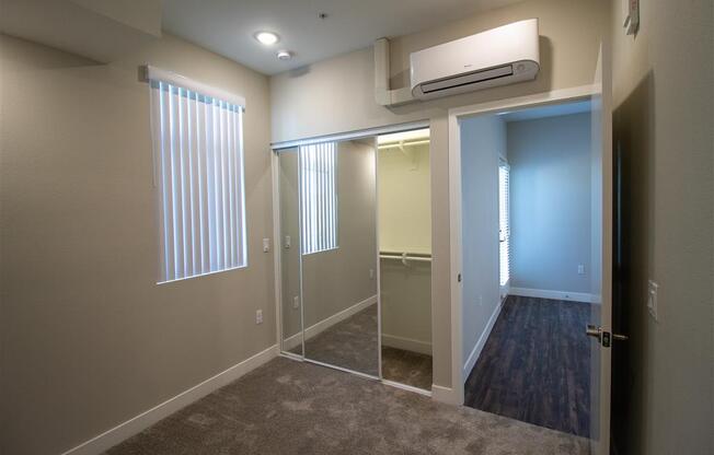 a bedroom with a walk in closet and a large window at Loma Villas Apartments, California, 92408