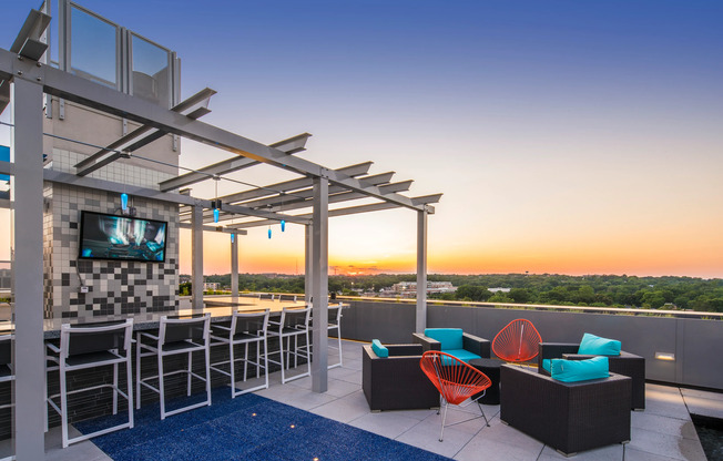 rooftopOutdoor lounge at our apartments for rent in Arlington, featuring outdoor couches, a TV, and string lights.
