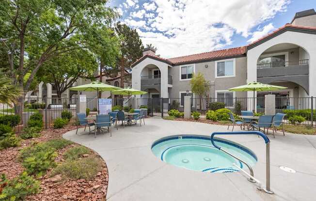 A pool area with a hot tub and chairs in front of a building.