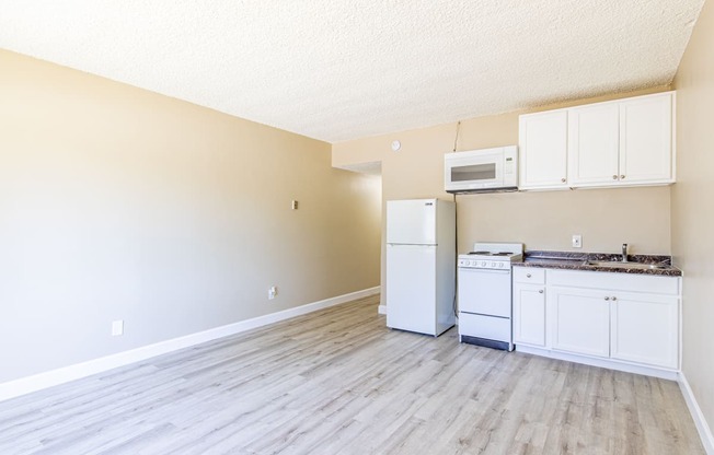 an empty kitchen with white appliances and white cabinets