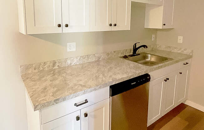 A kitchen with white cabinets and a granite countertop.