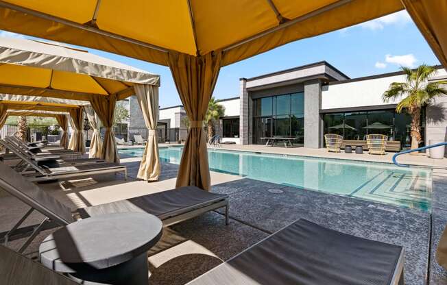 a pool with lounge chairs and umbrellas next to a building