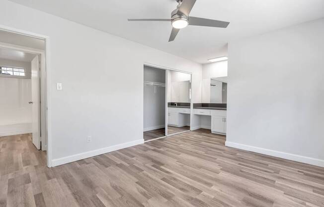 A room with a ceiling fan and wooden flooring.
