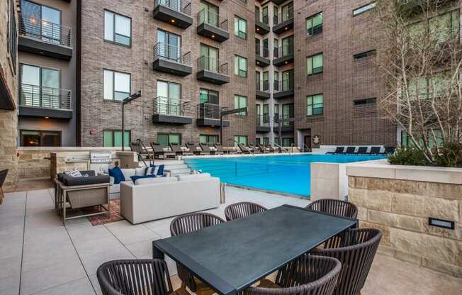 a patio with a table and chairs next to an apartment building