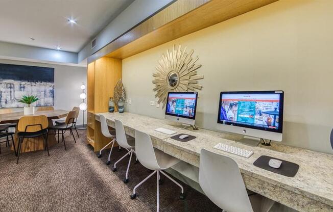 A room with a desk, chairs, and computer monitors.