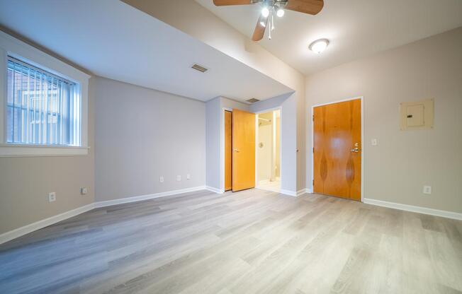 A room with a ceiling fan and a window with blinds.