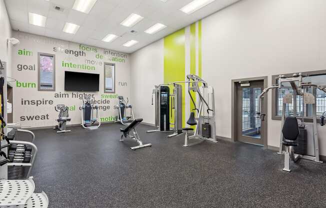 A gym with a variety of equipment and motivational words on the wall.