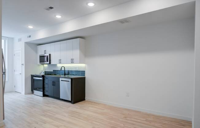 an empty room with a kitchen and a hard wood floor