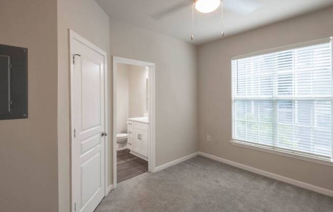 A well-lit, empty room with a toilet and sink visible through the open door.