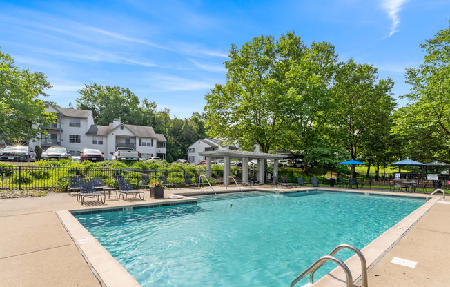 A swimming pool surrounded by trees and a building in the background.