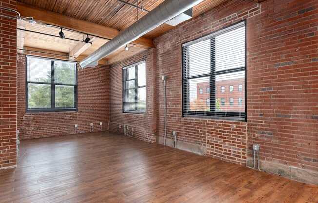 an empty living room with brick walls and wood floors