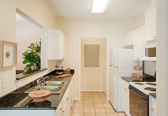 Galley kitchen with white cabinets, tile floors, granite countertops; laundry room