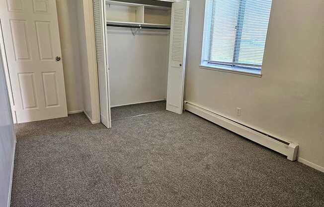 A bedroom with a closet and a large window at Waverly Park Apartments, Lansing