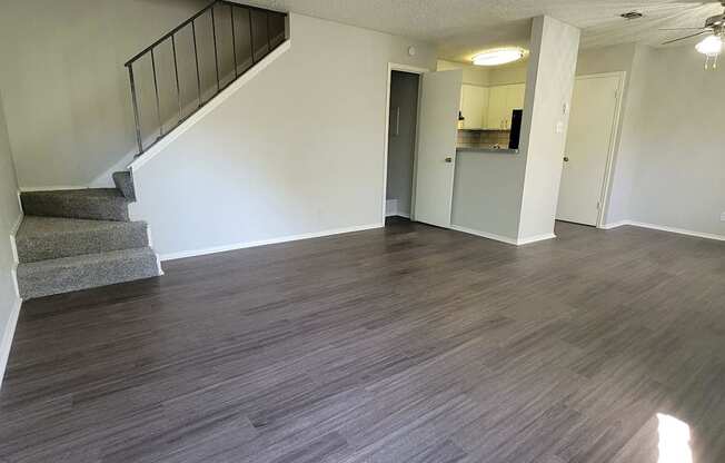 an empty living room with wood flooring and a staircase