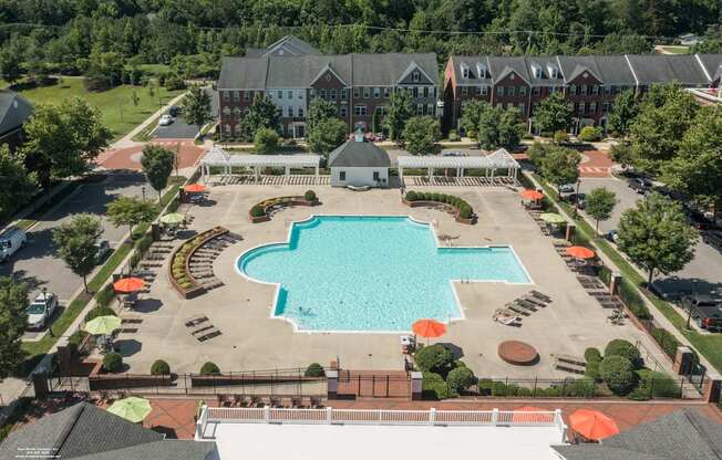 an aerial view of a swimming pool in front of a hotel with trees