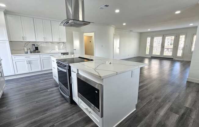 a kitchen with white cabinets and a large island with a stove and a microwave