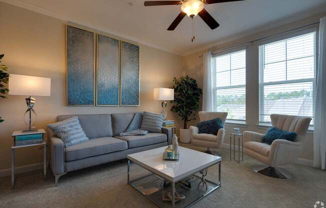 A living room with a grey couch, a white coffee table, and a ceiling fan.