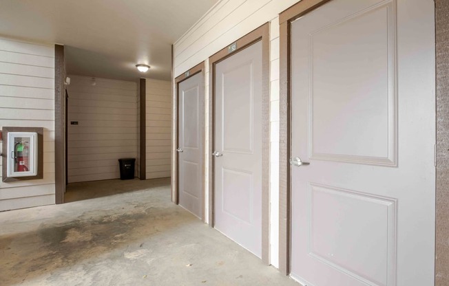 a row of doors in a hallway with a painting on the wall at Parc at Bentonville Apartments in Bentonville, AR