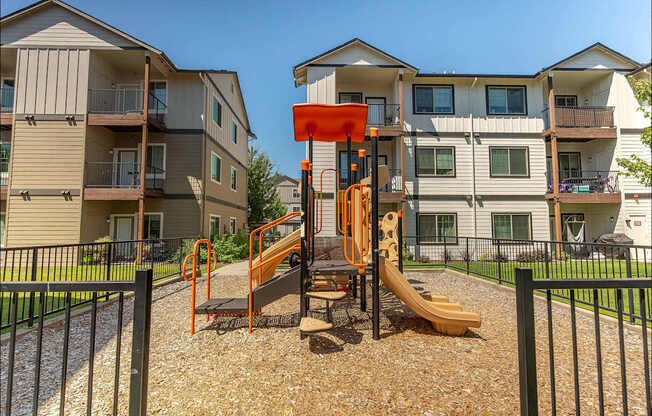 A playground with a slide and a wooden platform is in front of a building at Forestplace Apartment Homes, Forest Grove, 97116
