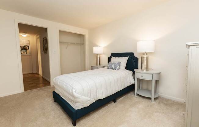 A bedroom with a bed, nightstand, and lamp.