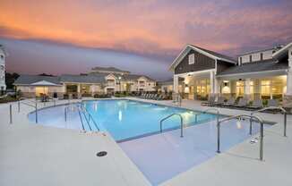 Resort-style swimming pool with shallow wading area and clubhouse patio at twilight at the Station at Savannah Quarters in Pooler, GA