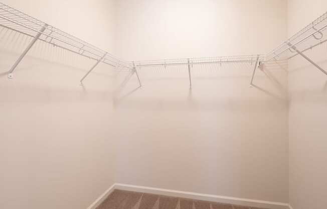 a room with white walls and wire racks on the ceiling