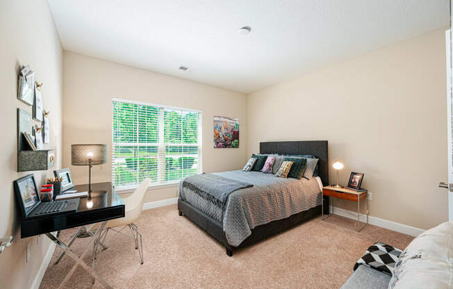 a bedroom with a bed and a desk and a window