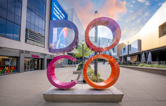 A large outdoor sculpture with three rings in pink, orange, and red.