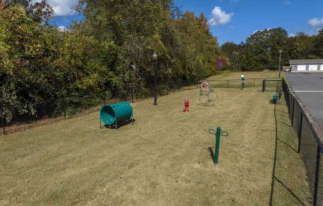 A playground with a green barrel and a red slide.