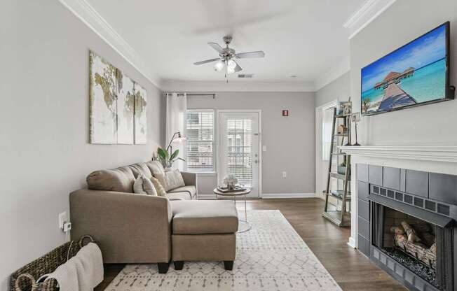 A living room with a couch, a chair, a rug, a fireplace, and a television.