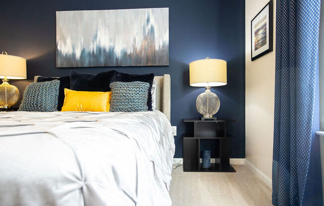 a bedroom with blue walls and a bed with yellow and blue pillows