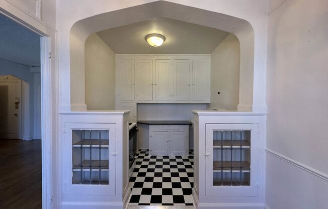 a kitchen with white cabinets and a black and white checkered floor