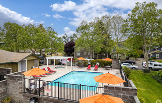 a swimming pool with orange umbrellas by pool