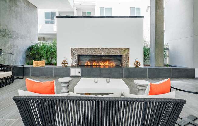 Outdoor dining area with a black chair in front of a fireplace at G12 Apartments in Los Angeles, CA