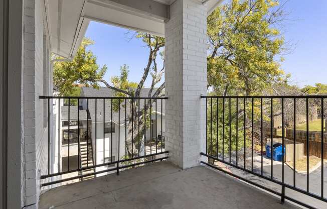 the view from the balcony of a home with a black railing and a white building