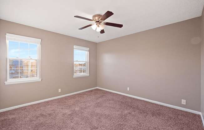 an empty room with carpet and a ceiling fan