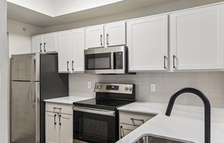 A kitchen with white cabinets and black appliances.
