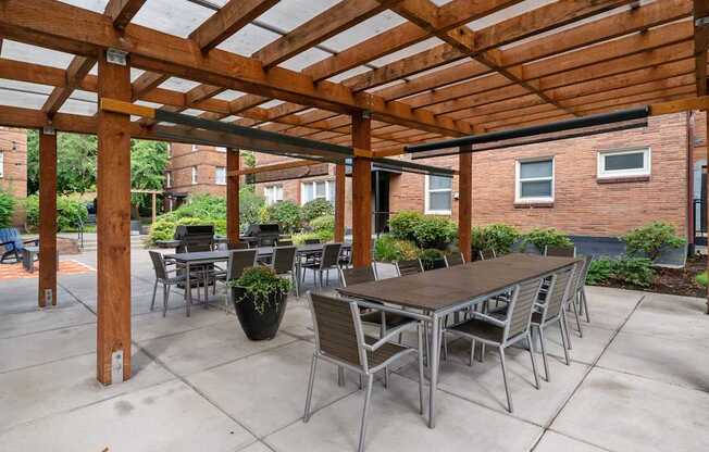 A wooden pergola with a table and chairs underneath.