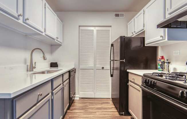 a kitchen with white cabinets and black appliances at The View Apartments St Charles, St Charles, IL