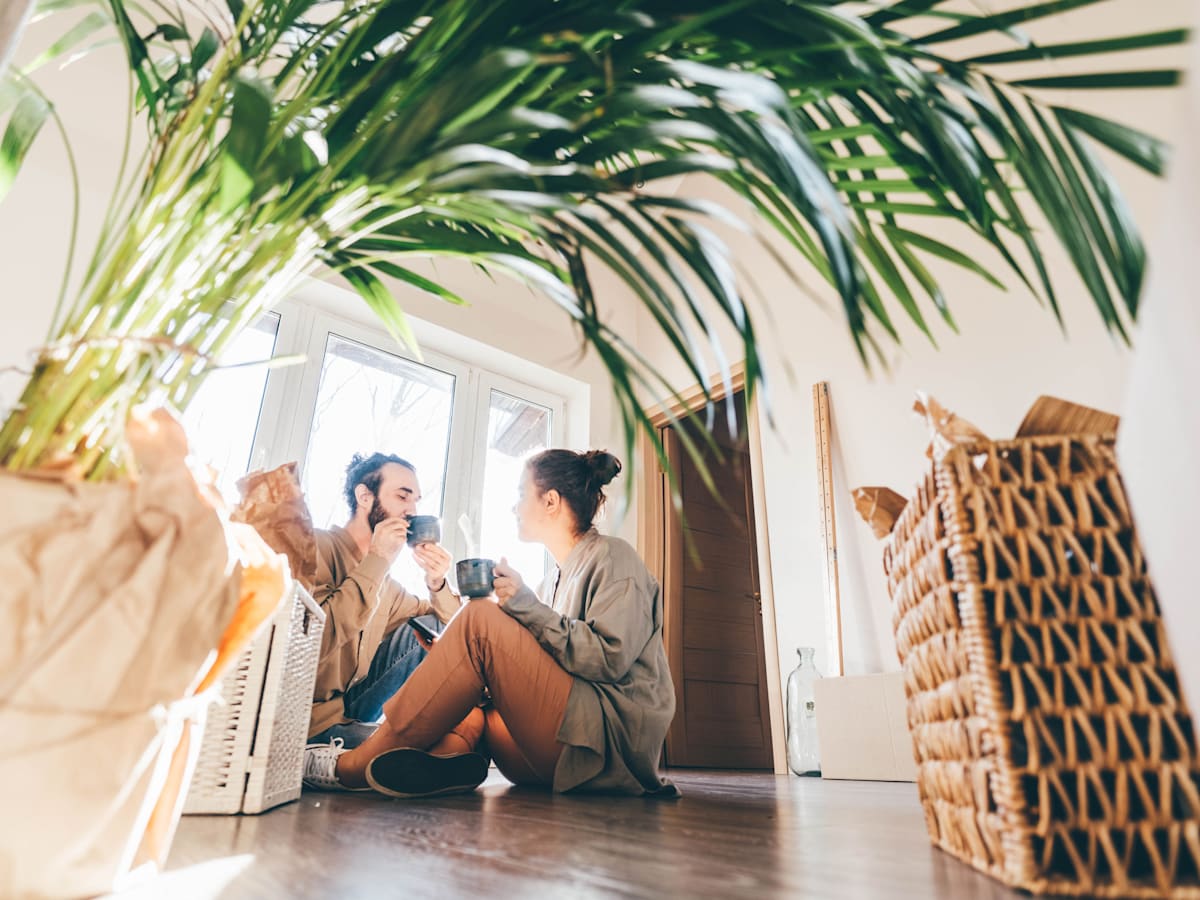 Two people sitting on the floor in a room with a large plant at Portofino Vineyards Apartment, Fort Myers, FL