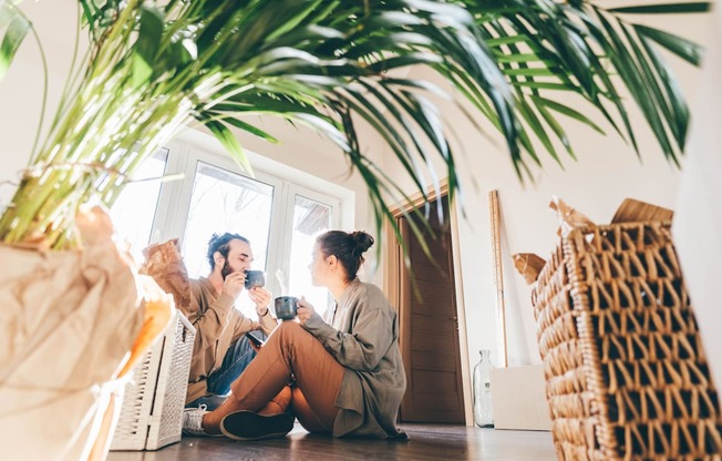 Two people sitting on the floor in a room with a large plant at Portofino Vineyards Apartment, Fort Myers, FL