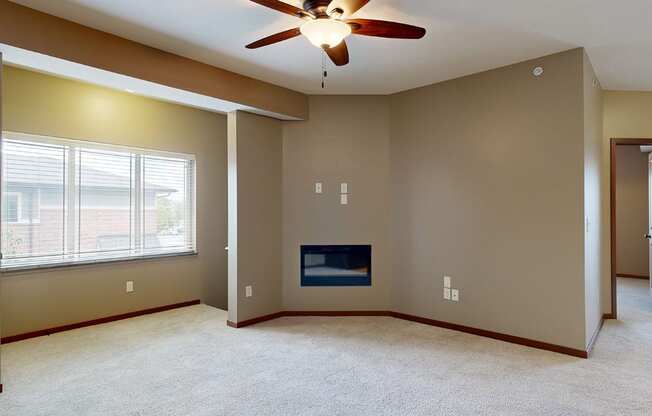 an living room with an electric fireplace, a ceiling fan, and large bay window above the stairs