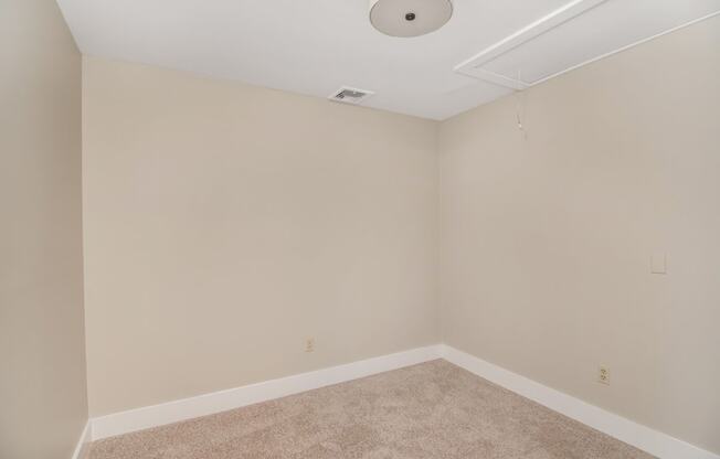 a empty room with beige walls and a ceiling fan