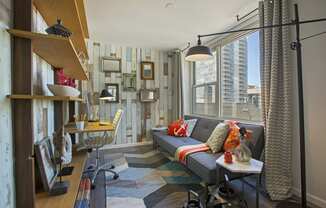 a small living room with a couch and a desk and a window