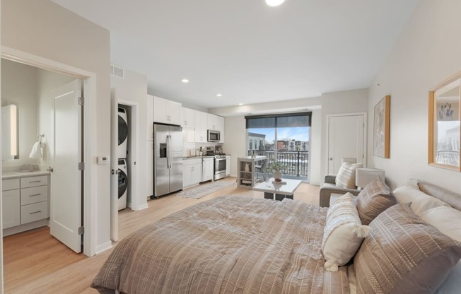 a bedroom with a couch and a bed and a kitchen with a window
