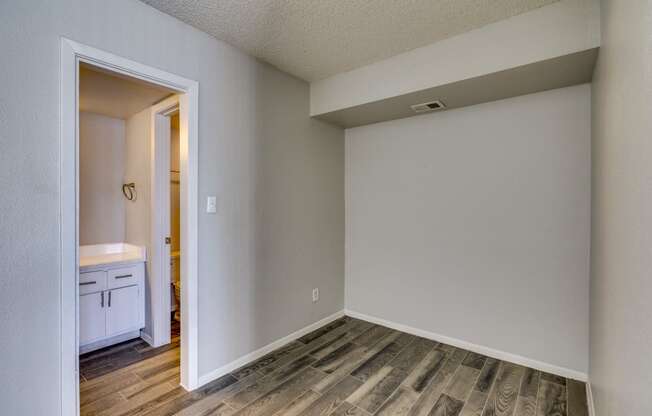 an empty room with wood flooring and a door to a bathroom