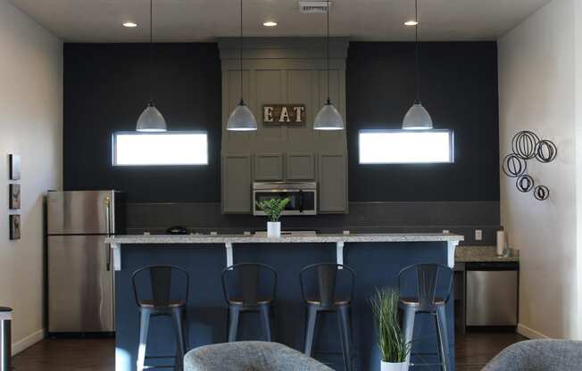 a kitchen with a bar with blue stools in front of it