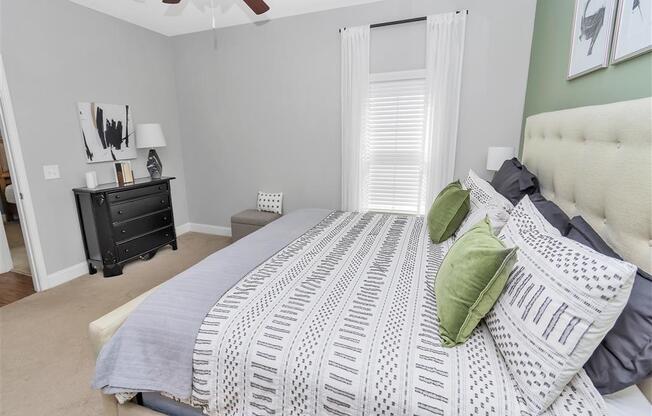 Bedroom with a slender tall window, ceiling fan, tan carpet, and doorway leading to a hallway